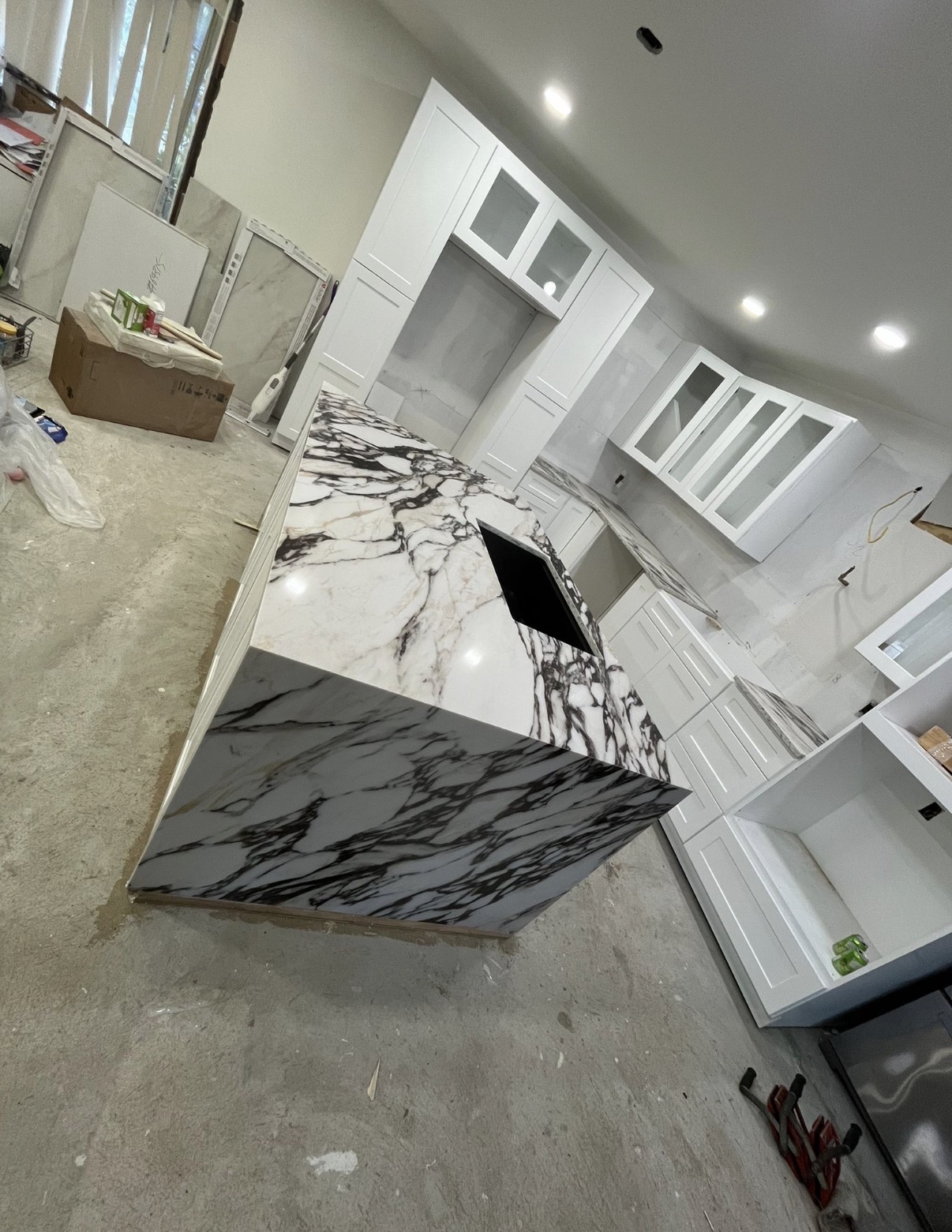 A kitchen renovation featuring quartzite countertops, floor-to-ceiling pantry cabinets, glass display cabinets, and rich burgundy cabinetry.